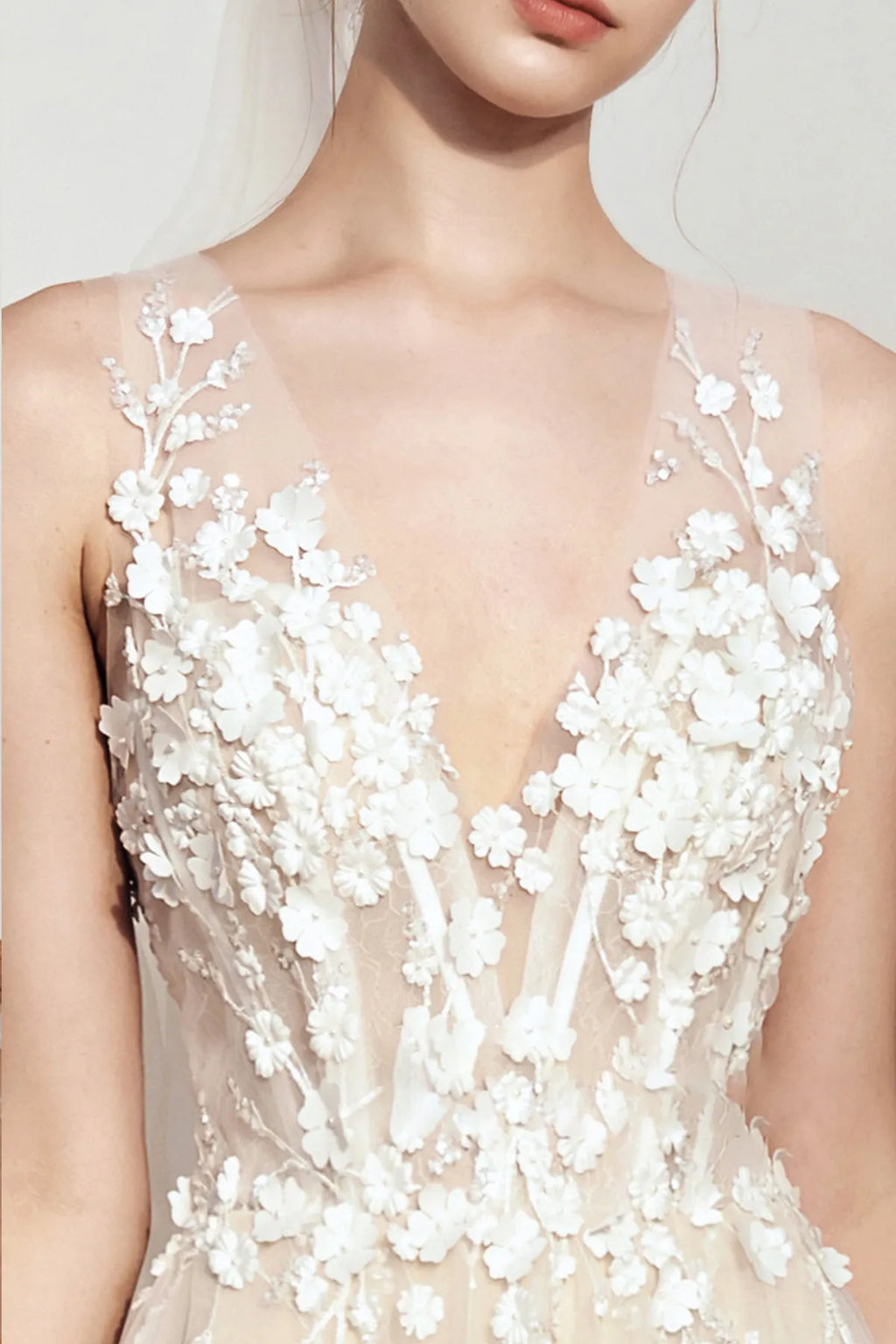 Close-up of a deep V-neck bridal bodice decorated with intricate 3D floral appliqués and beaded vine embroidery