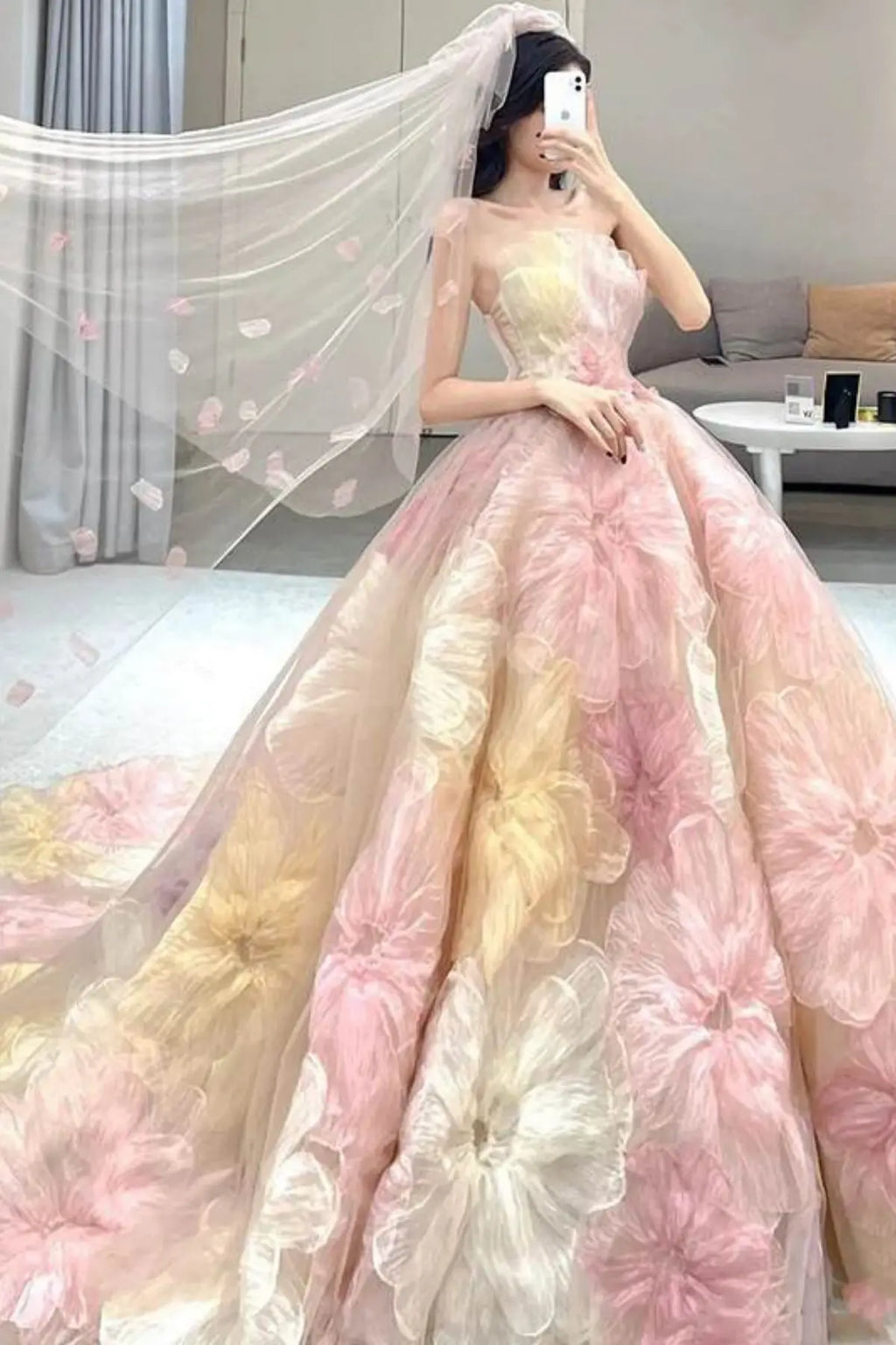 Front view of a strapless pastel blush pink wedding ball gown featuring voluminous 3D organza flower appliques in shades of pink, cream, and soft yellow