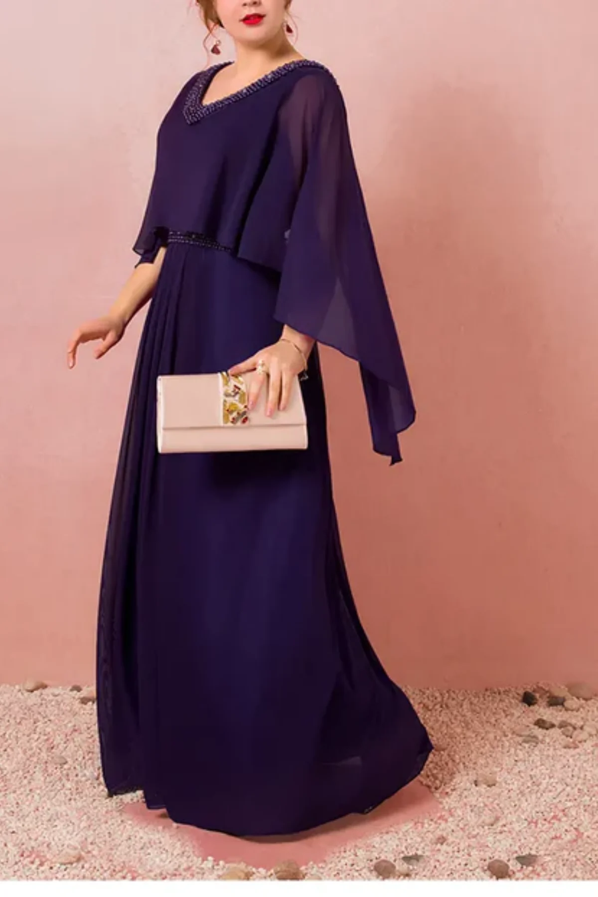 Side view of navy chiffon mother of the bride gown with beaded waist detail, flowing cape sleeves, and soft pleated skirt in motion