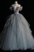 Front full-length view of an ethereal dove grey wedding gown with a layered tulle A-line skirt and a draped off-the-shoulder sweetheart bodice