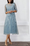 Front view of mist blue lace mother of the bride dress with illusion neckline and tea-length skirt
