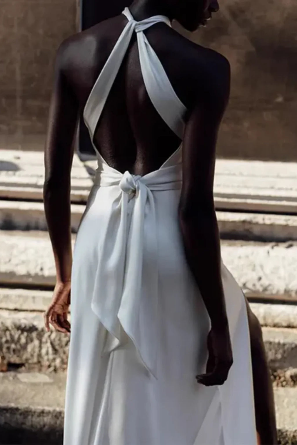 Luxury satin halter wedding dress with open back, tied bow detail, and sleek silhouette