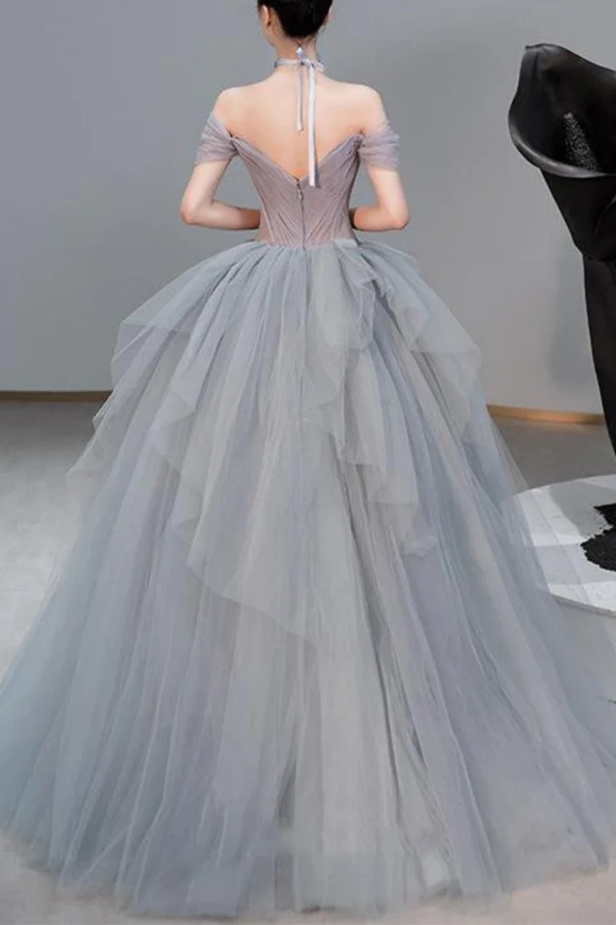 Rear view of a light grey A-line bridal gown showing a low-cut back with a concealed zipper closure and a soft tulle sweep train