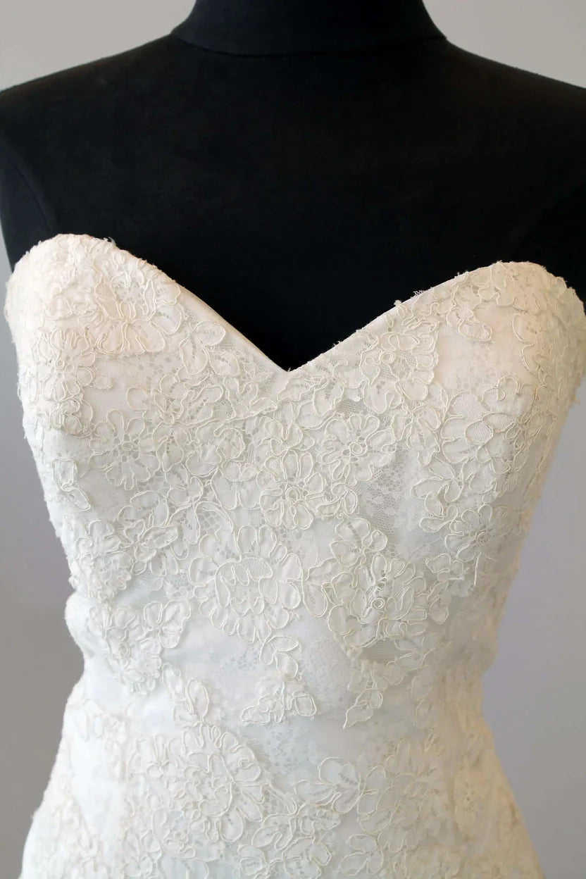 Romantic strapless lace bridal gown featuring a sweetheart neckline, drop waist silhouette, and flowing lace train