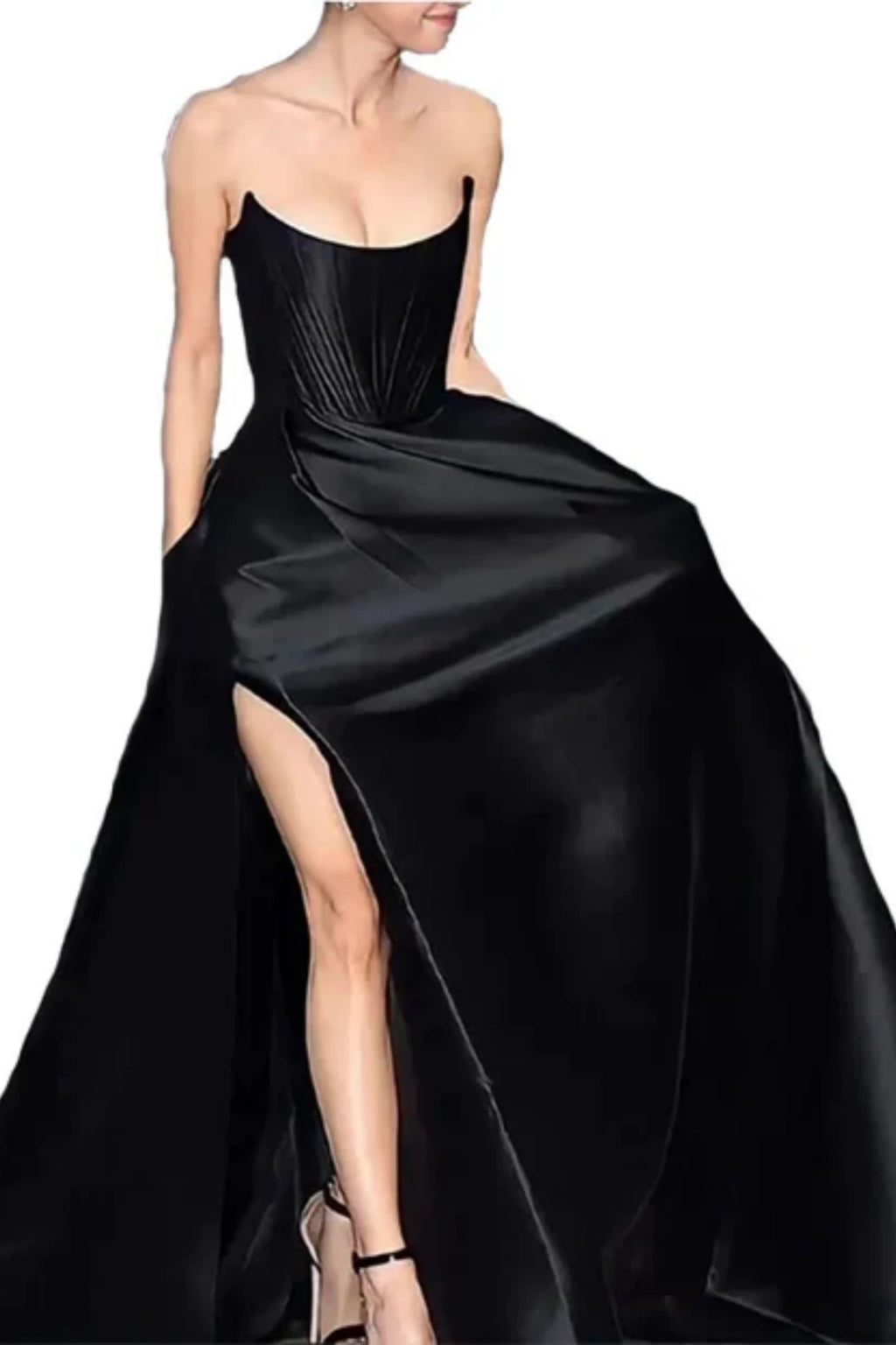 Model showcasing the high leg slit of a dramatic black satin ball gown, paired with black ankle-strap high heel shoes against a plain white backdrop