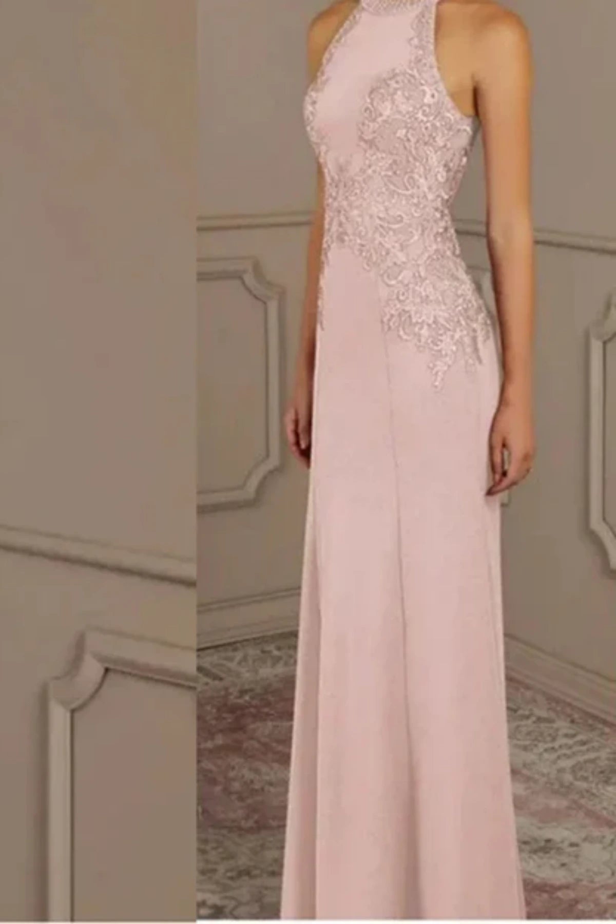 side full-length view of a pastel pink mother of the groom dress featuring a beaded halter neckline, lace appliqués on the bodice, and a fitted mermaid skirt on a mannequin