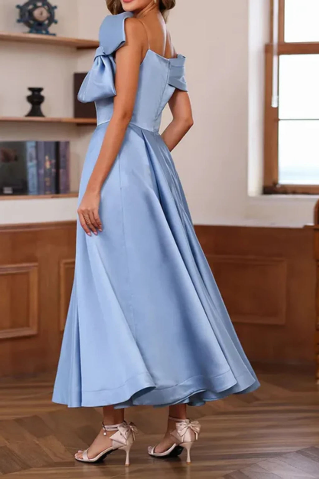 Side profile of a blue satin A-line formal dress on a mannequin, demonstrating the functional hidden side pockets in the pleated midi skirt