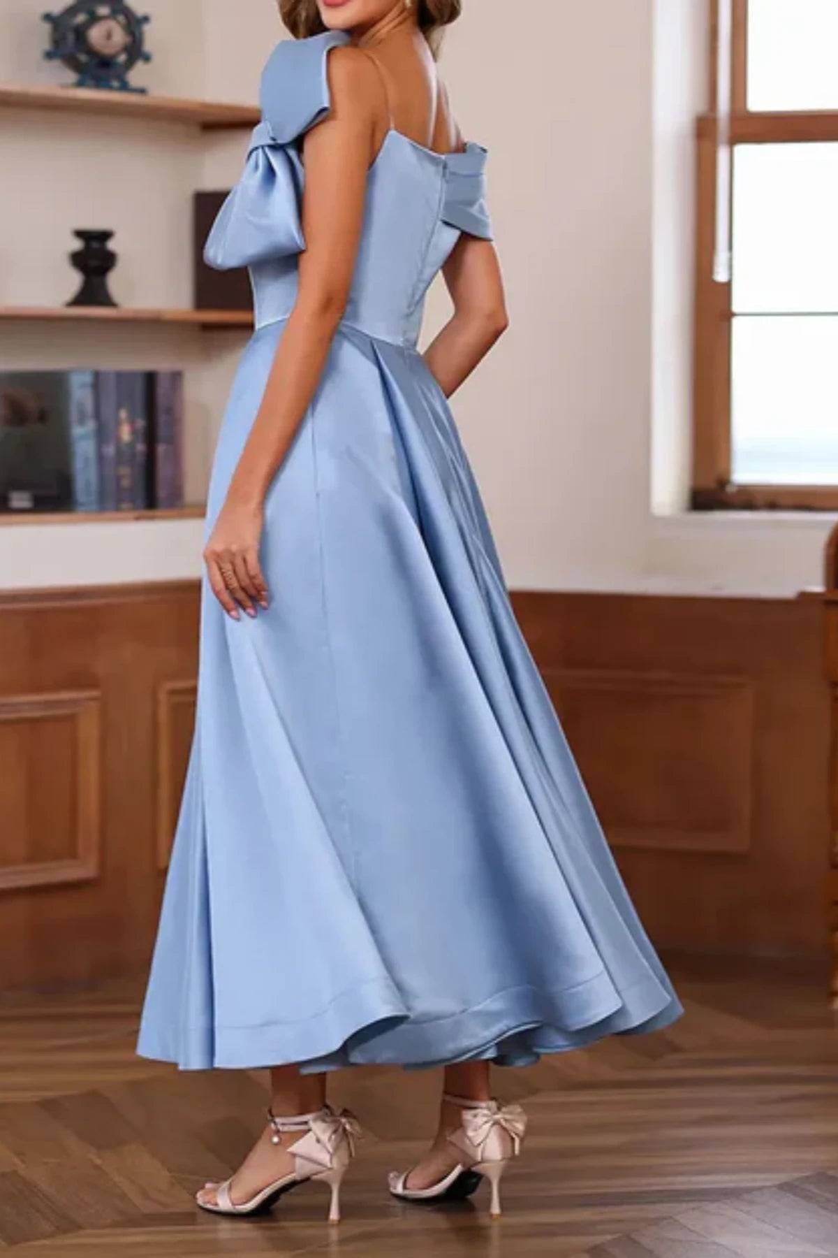 Side profile of a blue satin A-line formal dress on a mannequin, demonstrating the functional hidden side pockets in the pleated midi skirt