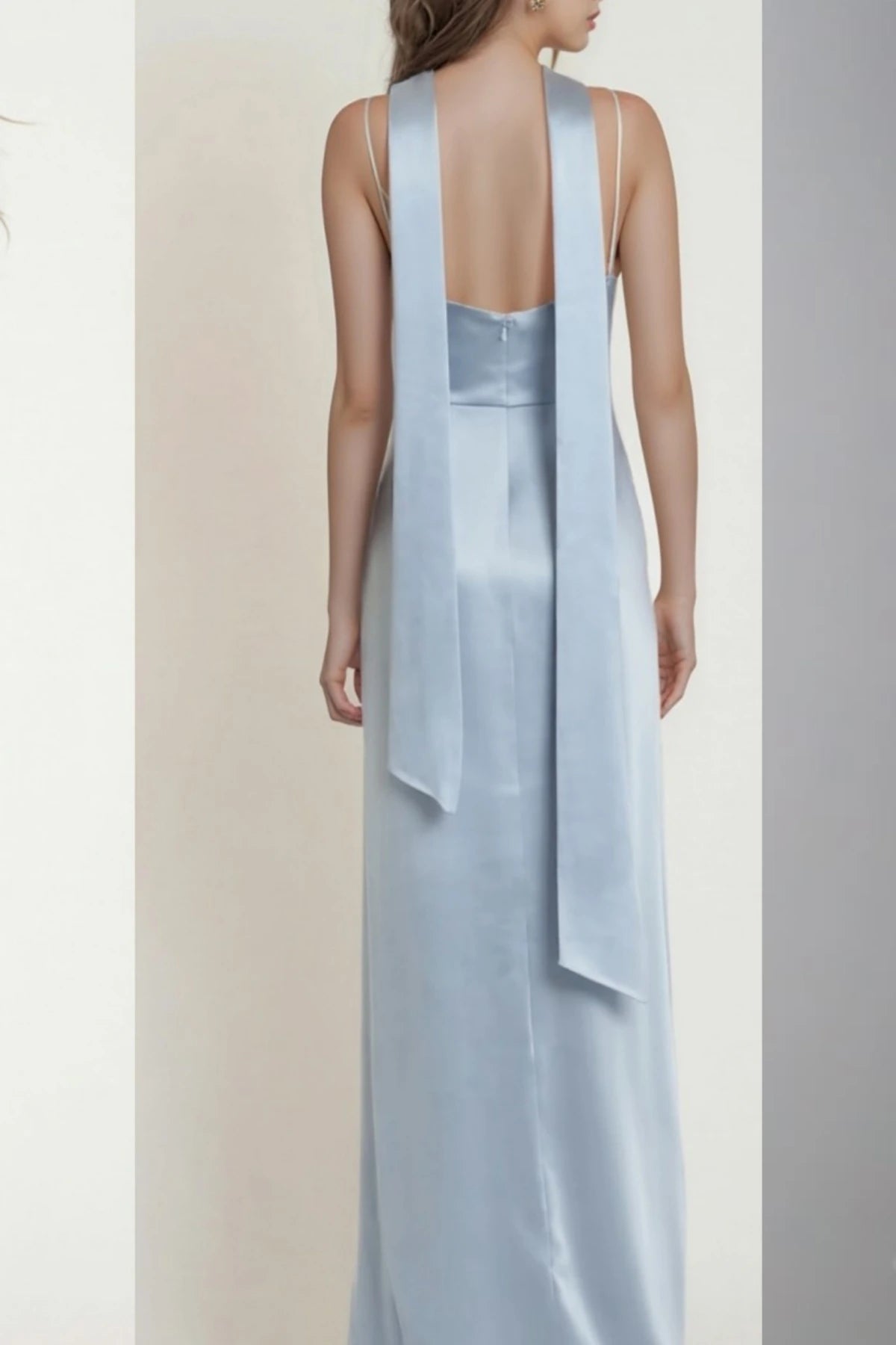Back view of dusty blue satin bridesmaid dress showing its straps and flowing floor-length skirt
