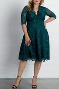 Full-length front view of an emerald green knee-length mother of the bride dress, featuring a V-neckline, elbow sleeves, and a beaded satin belt