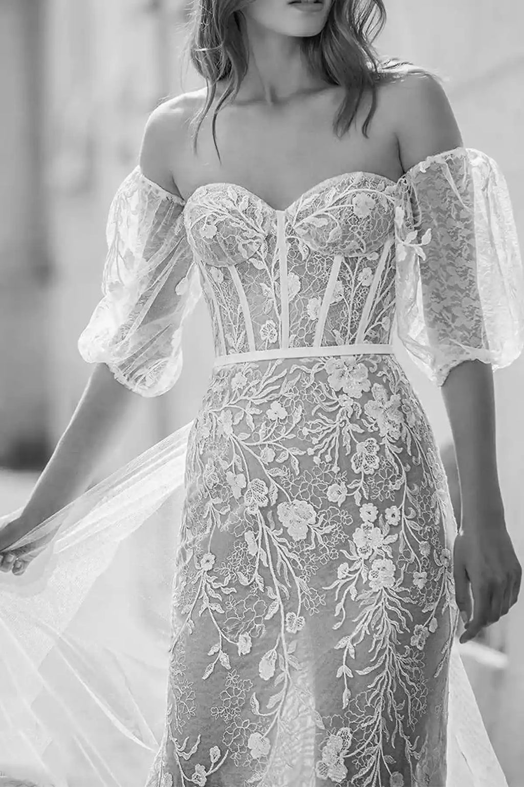 Front close-up portrait of the bridal gown highlighting the structured sweetheart corset bodice with exposed boning and delicate sheer lace sleeves