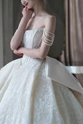 Side view of a model wearing a champagne tulle wedding dress, highlighting the romantic draped off-the-shoulder sheer sleeves and delicate floral trailings