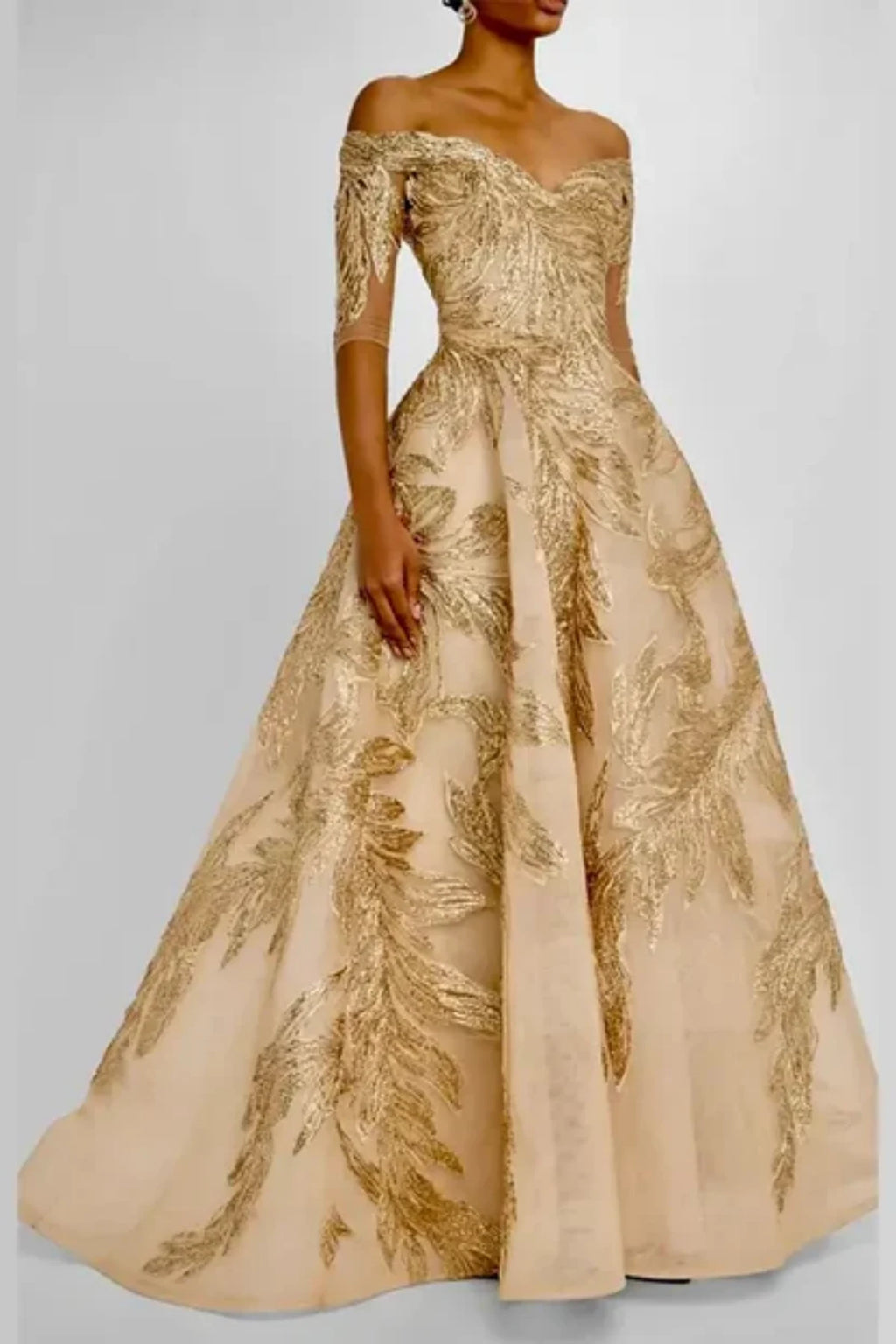 Close-up of the bodice on a champagne gold formal gown, displaying a structured off-the-shoulder neckline, mid-length sleeves, and detailed gold vine and feather embroidery