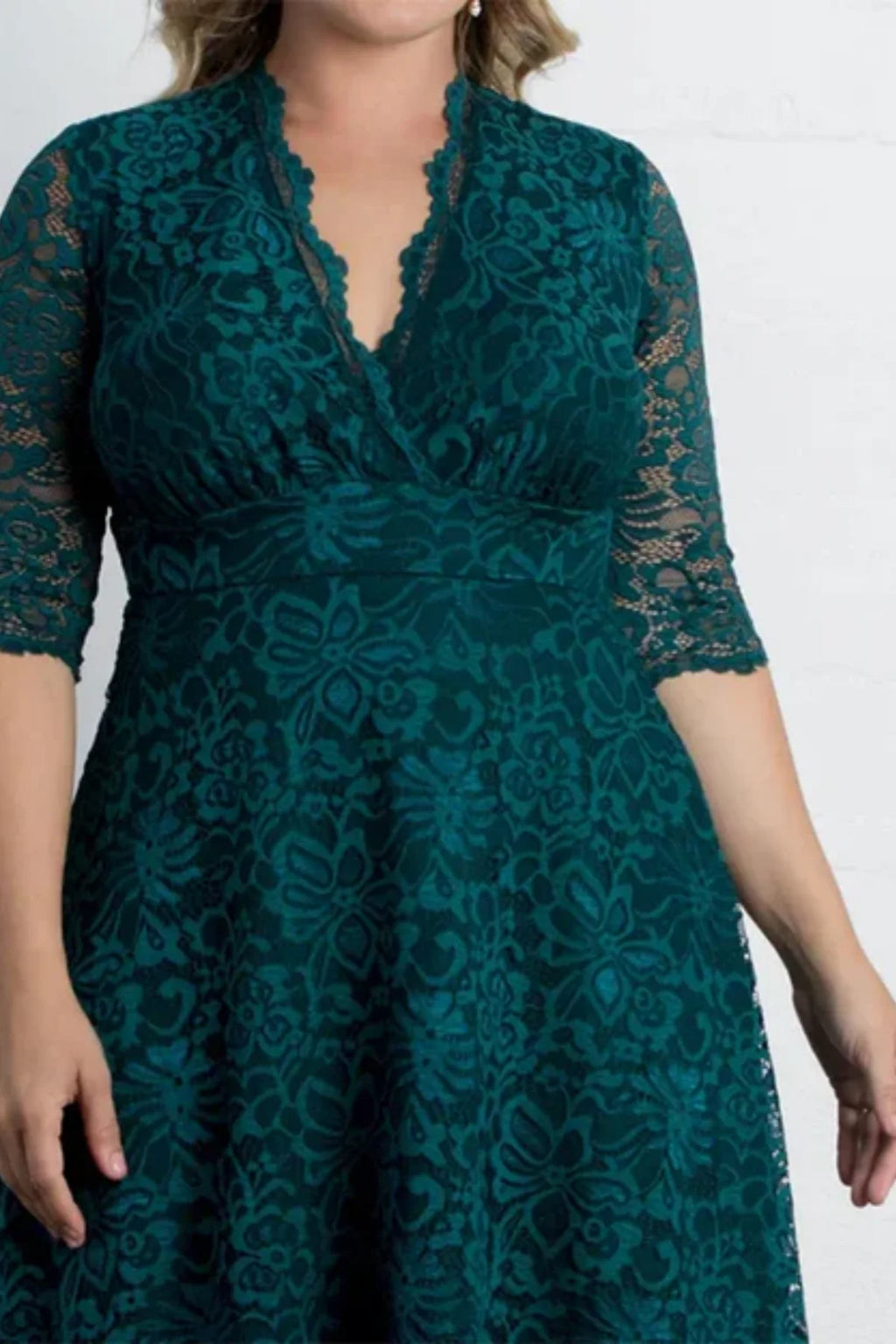 Close-up of the bodice on a forest green lace evening dress, highlighting the scalloped V-neckline, sheer half sleeves, and a cinched waistline