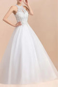 Front three-quarter view of a model in a white A-line wedding dress featuring a high halter neckline with a small front keyhole cutout and an intricately beaded bodice