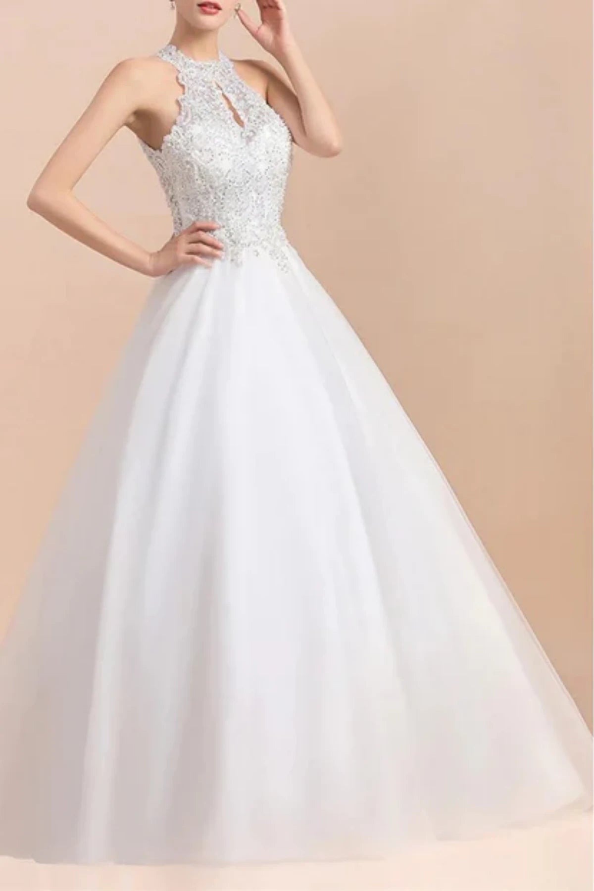 Front three-quarter view of a model in a white A-line wedding dress featuring a high halter neckline with a small front keyhole cutout and an intricately beaded bodice