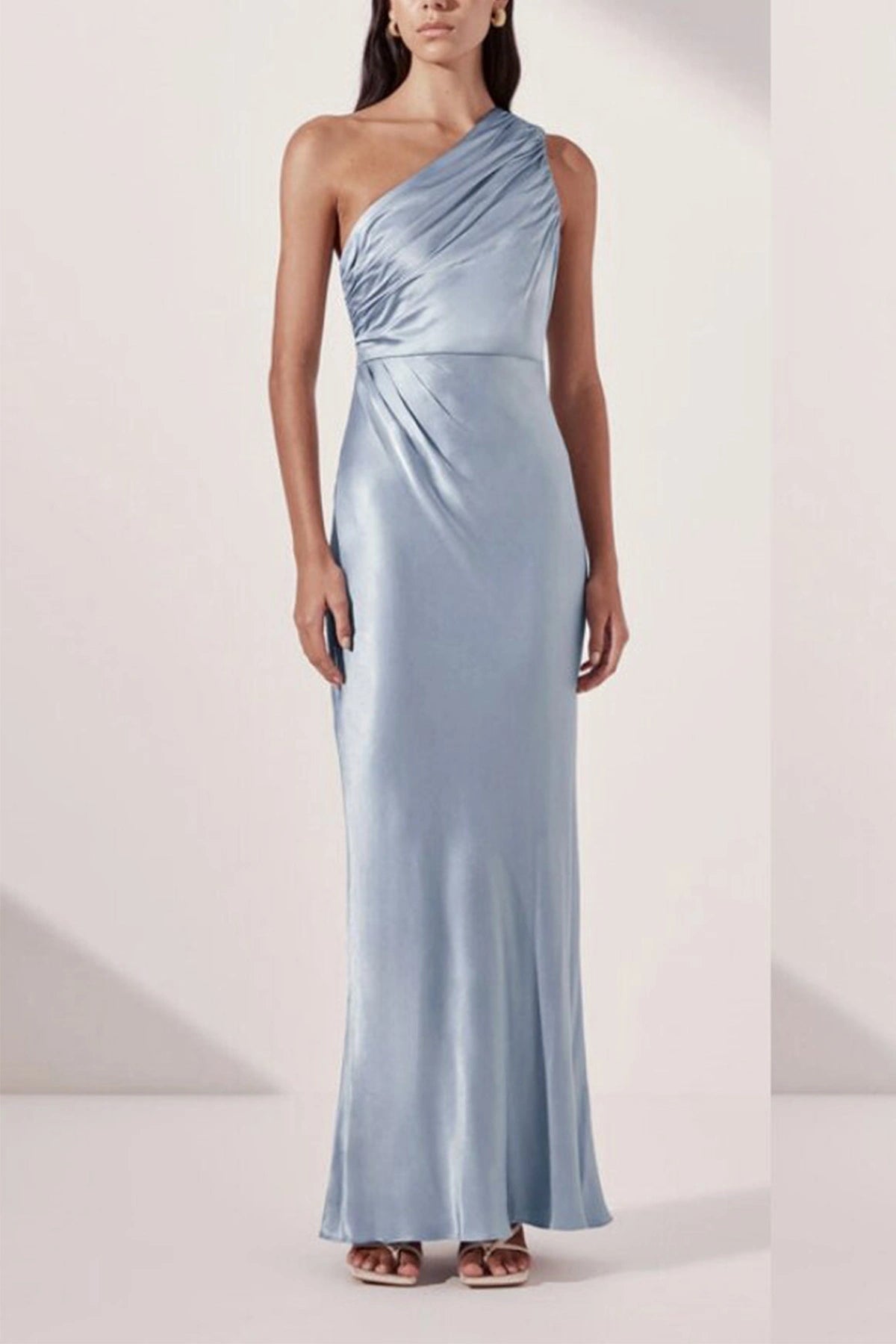 Front full-length view of an ice blue satin one-shoulder bridesmaid dress with diagonal ruched bodice and column silhouette.