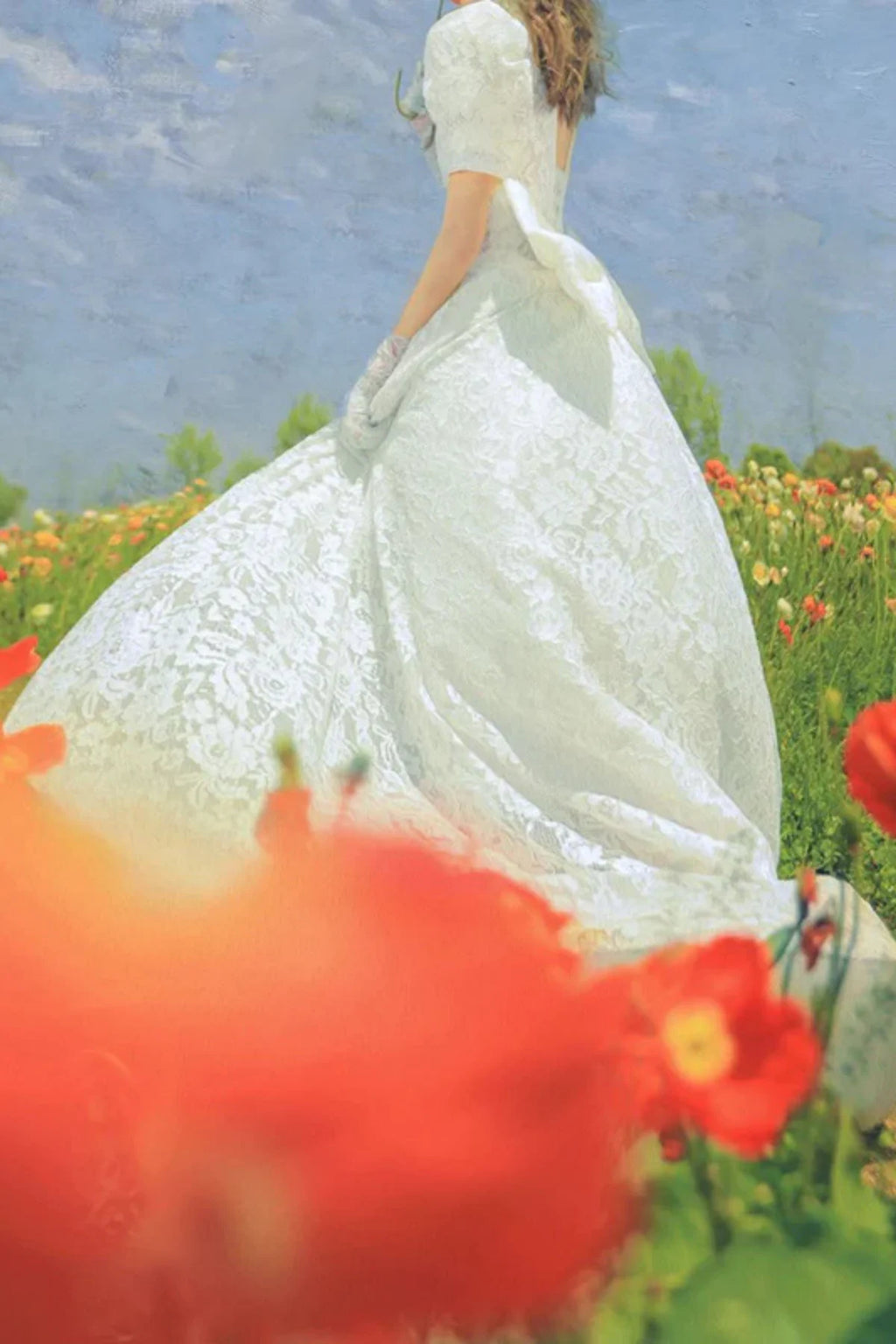 Vintage lace tea-length wedding dress with back bow detail in a colorful garden setting