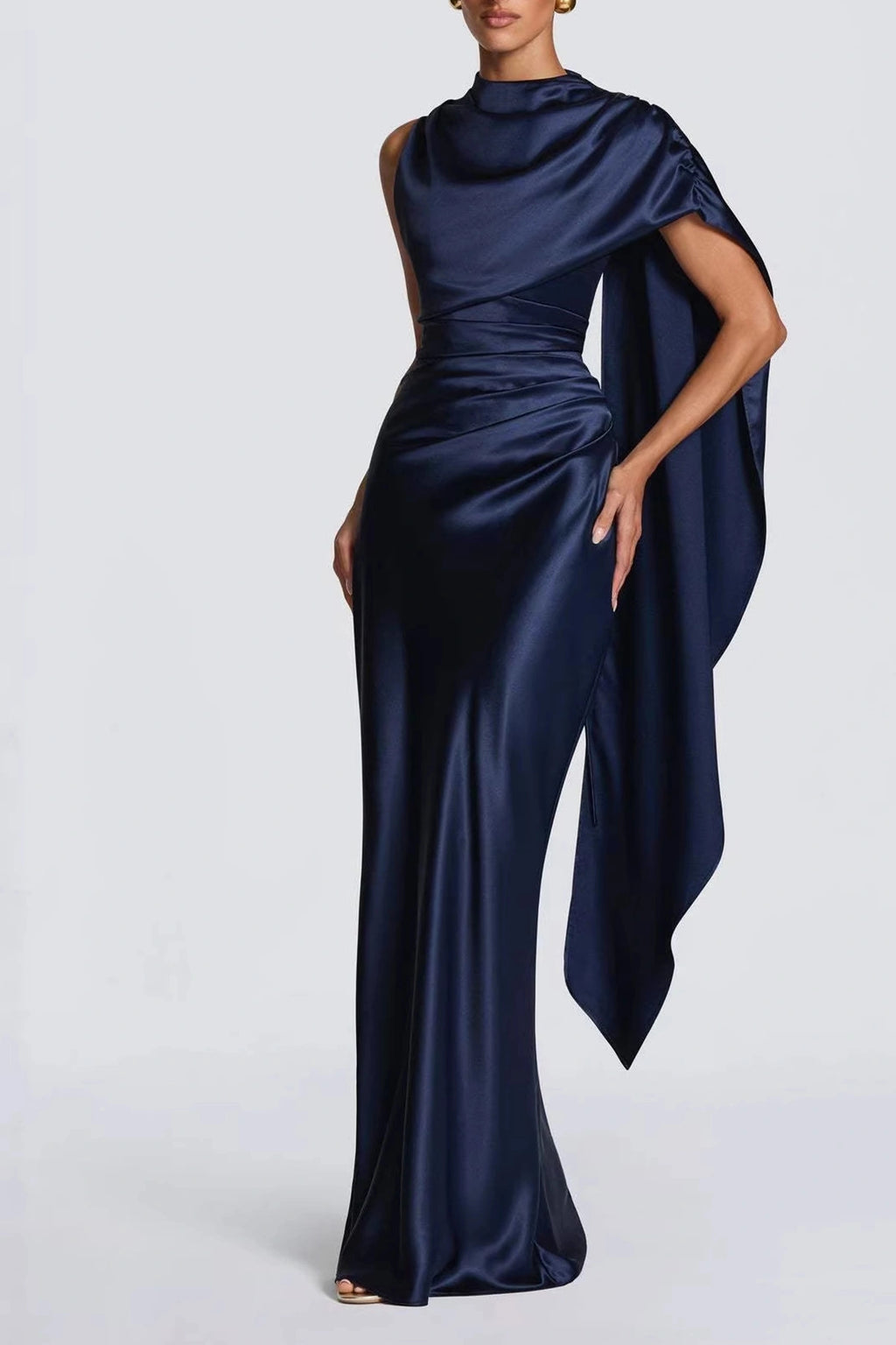 Front view of a midnight navy blue satin high-neck mother of the bride gown featuring an asymmetric draped cape sleeve and ruched waist