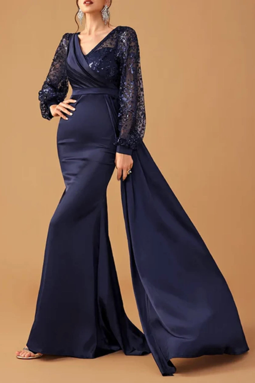 Angled front view of a dark navy blue satin formal trumpet dress on a mannequin, highlighting the flared lower skirt and sculptural sleeve ruffles