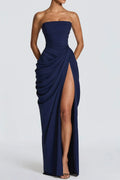Studio front view of a midnight navy blue strapless corset formal dress featuring asymmetrical hip gathering and a high leg slit