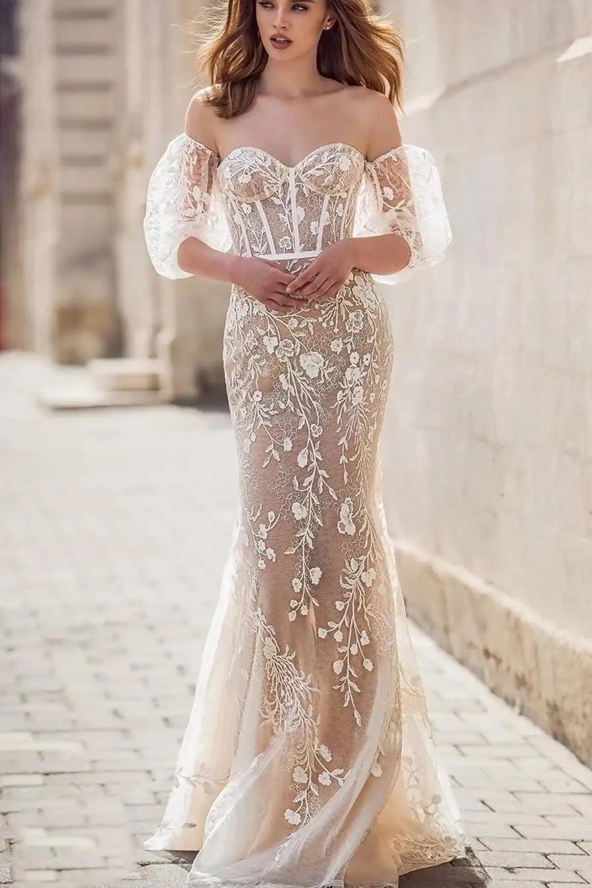 Front view of a model posing in a boho lace mermaid wedding dress, showcasing the close-fitting silhouette and the romantic flair of the flared lower skirt.