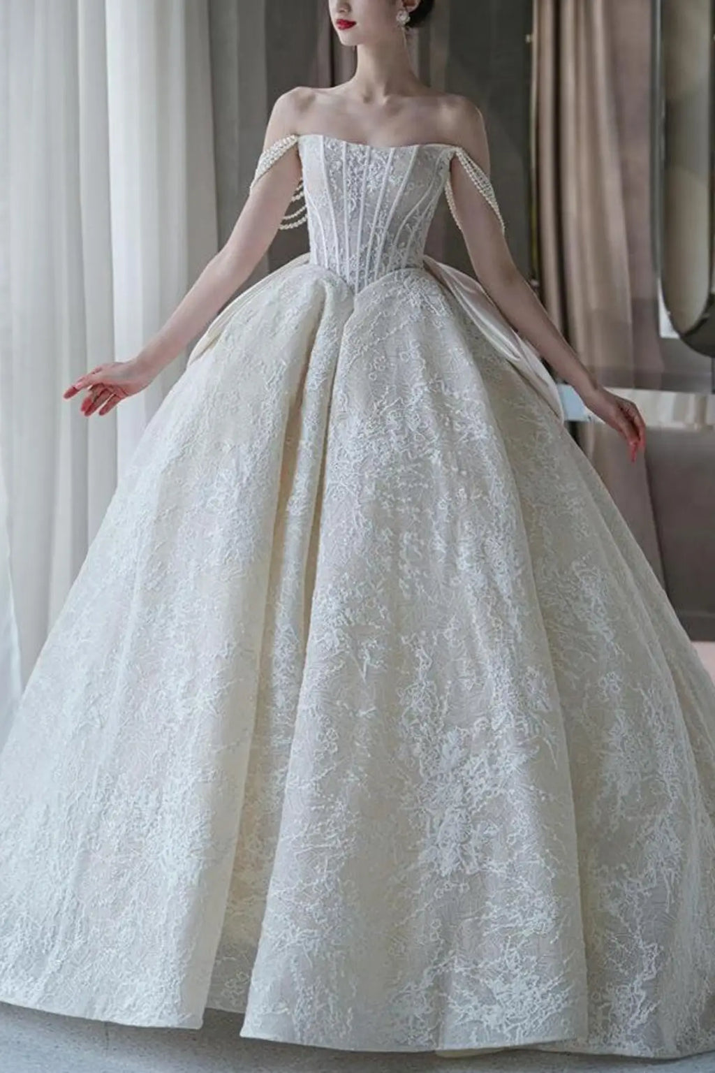 Front full-length view of a champagne-colored A-line wedding dress featuring  floral embroidery along the corset bodice and flowing tulle skirt