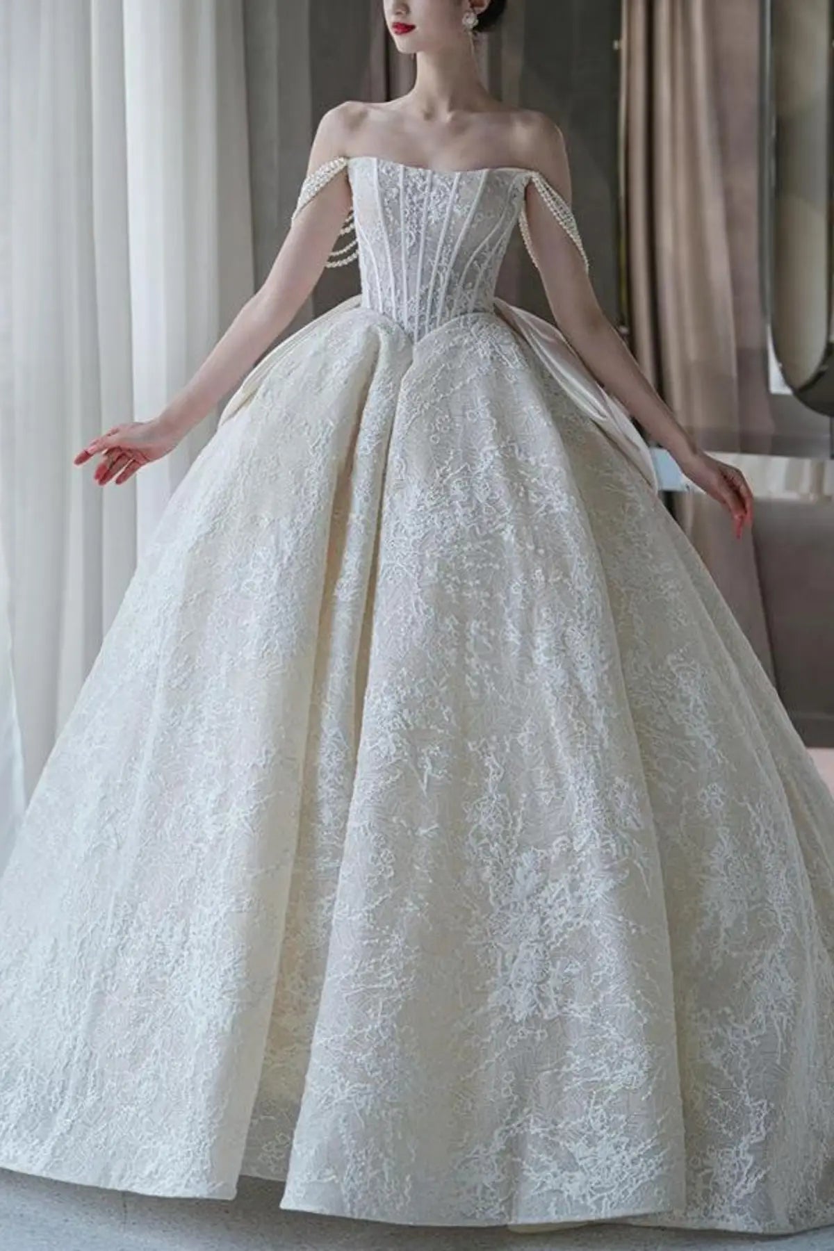 Front full-length view of a champagne-colored A-line wedding dress featuring  floral embroidery along the corset bodice and flowing tulle skirt