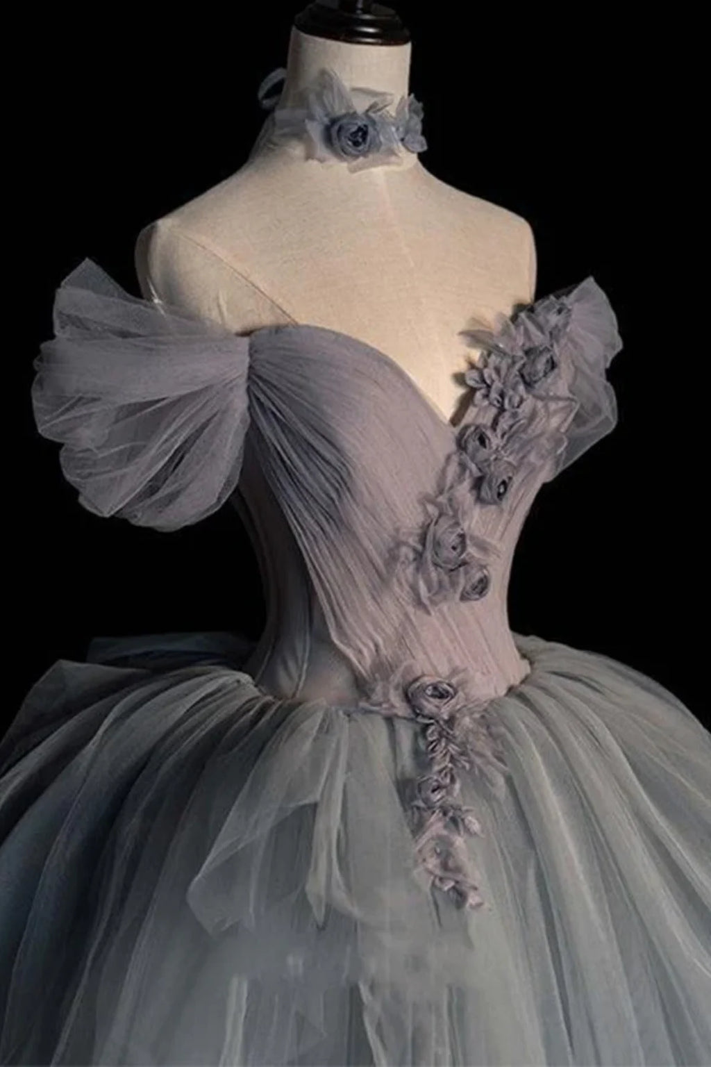Front three-quarter view of a light grey tulle bridal gown showcasing the romantic crossover pleated detailing on the sweetheart neckline bodice