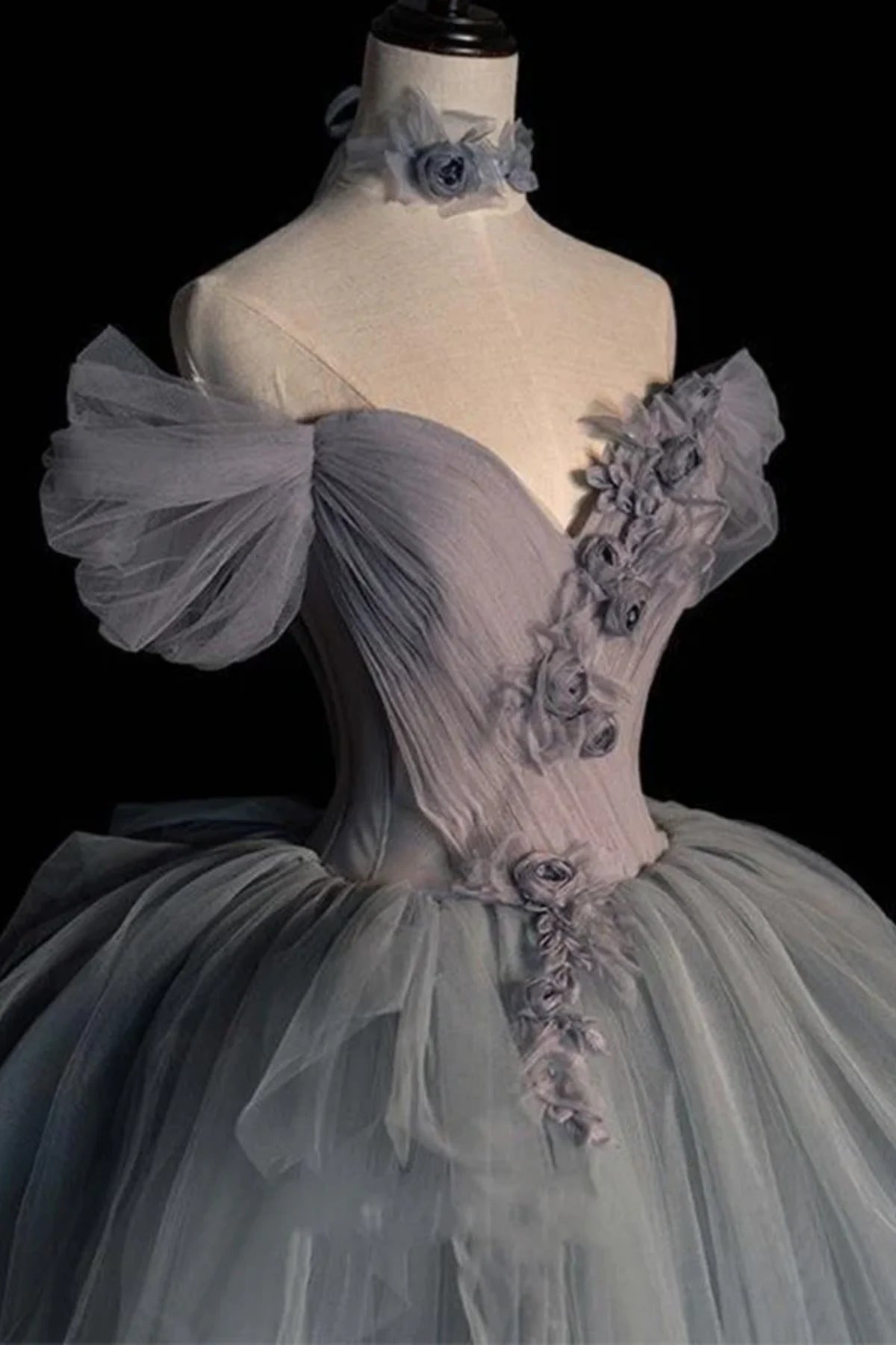 Front three-quarter view of a light grey tulle bridal gown showcasing the romantic crossover pleated detailing on the sweetheart neckline bodice