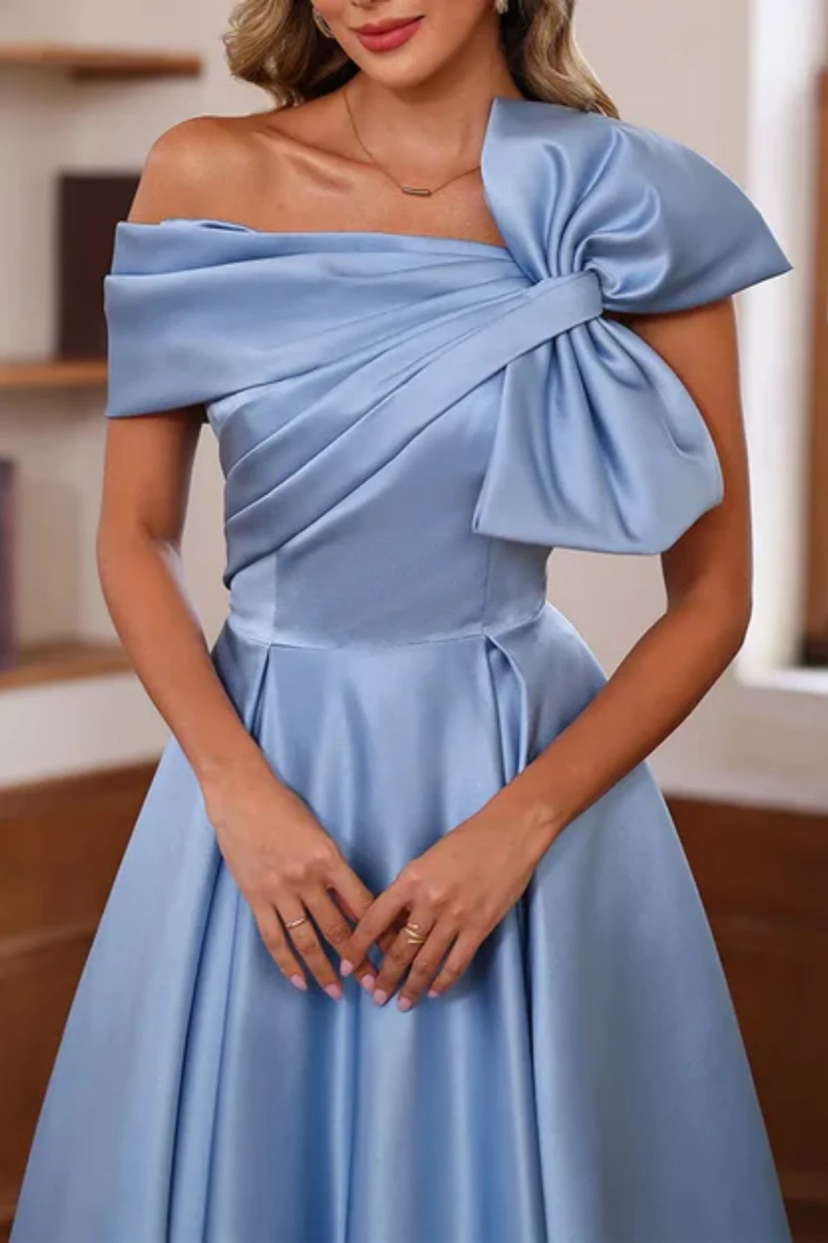 Close-up of the bodice on a blue satin evening gown, highlighting the structured cross-over ruching and supportive off-the-shoulder portrait collar neckline