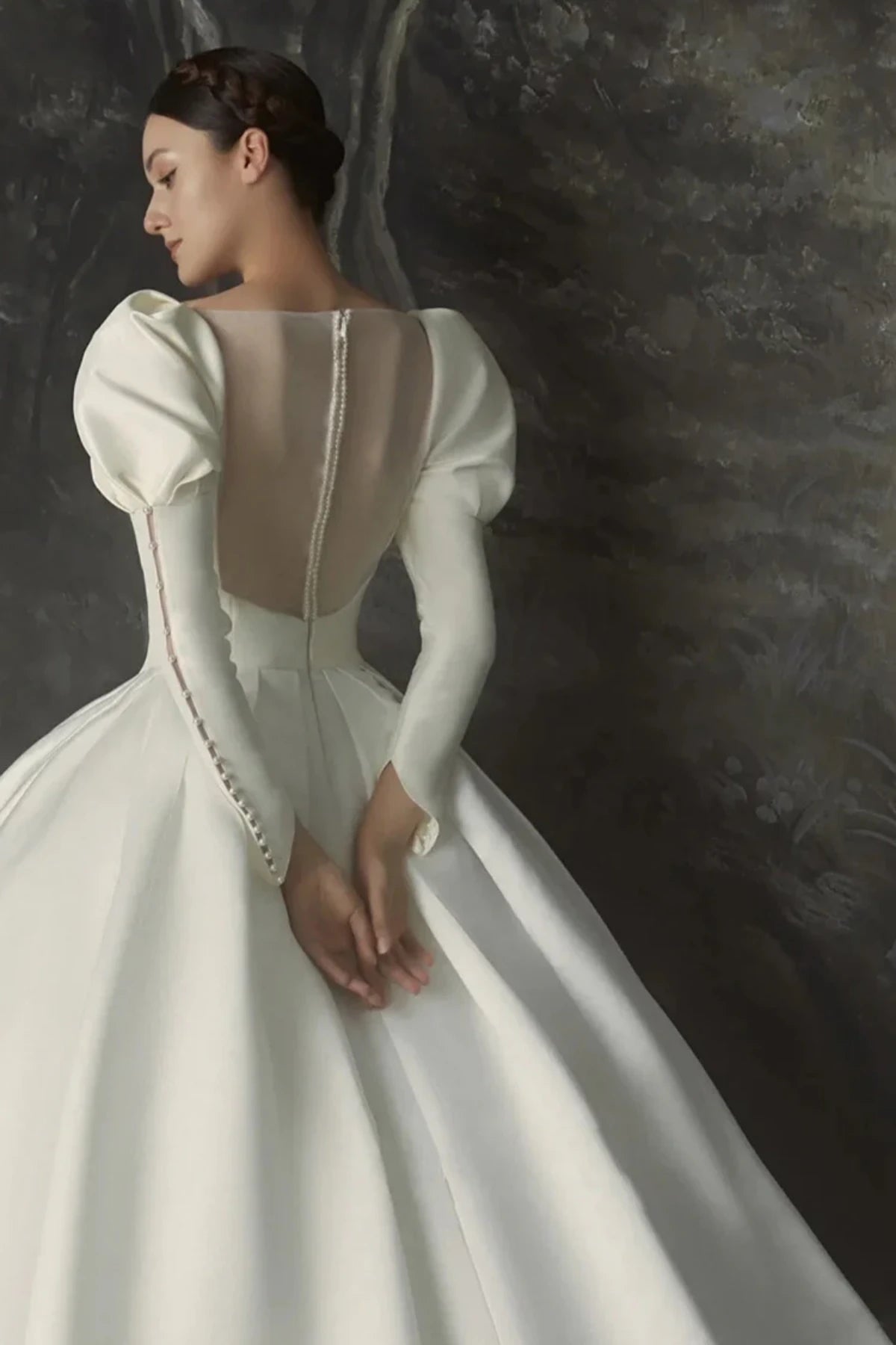 Elegant satin A-line wedding dress with sheer illusion back, button detailing, and long fitted sleeves