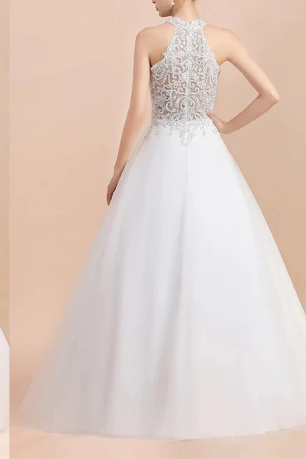 Rear view of a white A-line bridal gown showcasing a sheer illusion halter back adorned with intricate silver lace embroidery and beaded scroll patterns