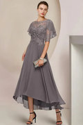 Full-length front view of a slate grey mother of the groom dress on a mannequin, featuring a fit-and-flare skirt and a sheer attached capelet with matching floral lace appliqués