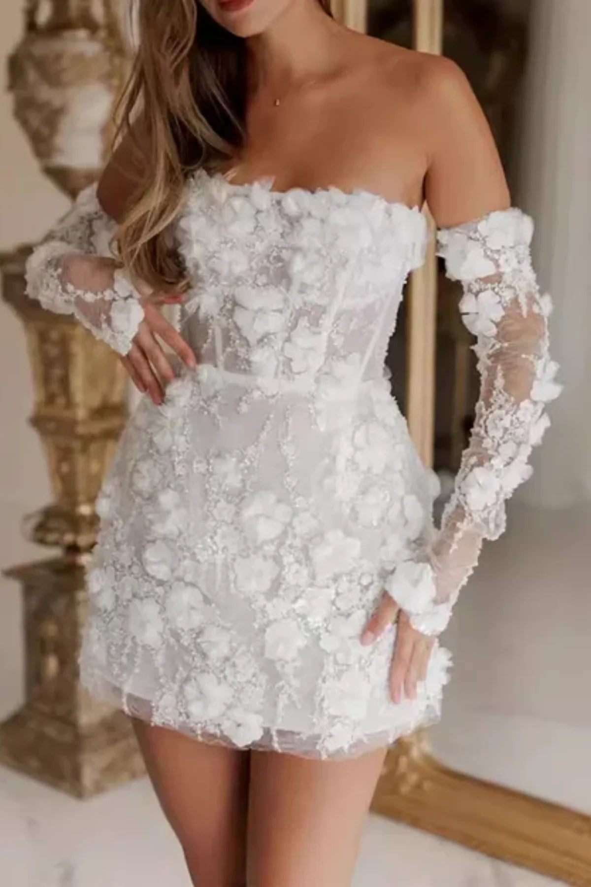 Front view of a strapless white mini wedding dress covered in textured 3D flower appliqués, featuring a sheer corset bodice and matching off-the-shoulder lace sleeves