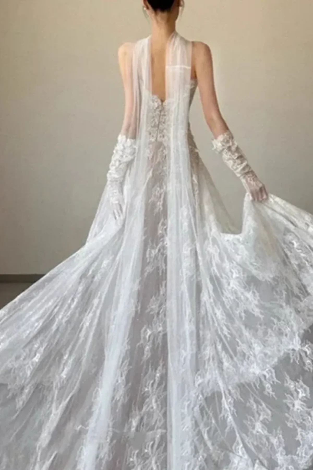 A regal long-sleeved wedding dress featuring a dramatic flared skirt and a sparkling lace train