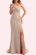 Full front view of a taupe satin mother of the bride dress displaying heavy asymmetric ruching, a fitted column-mermaid silhouette, and a high front slit on a mannequin