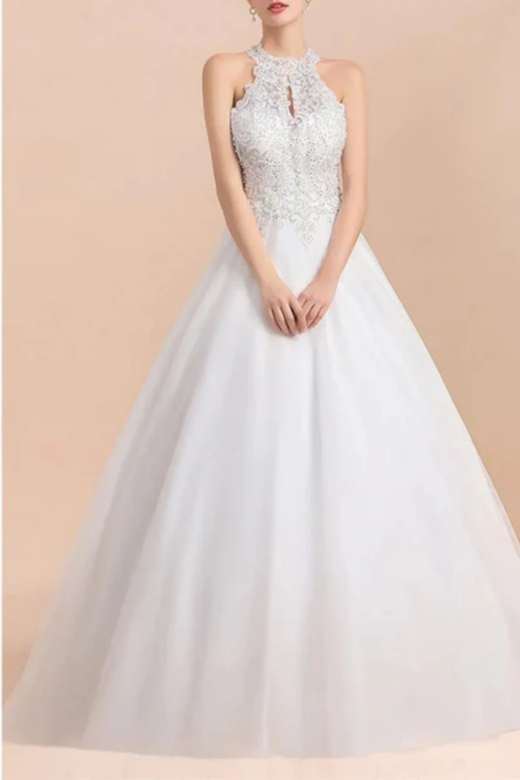 Front full-length portrait of a white tulle A-line wedding dress with a heavily crystal-embellished halter bodice and a smooth, volumized tulle floor-length skirt